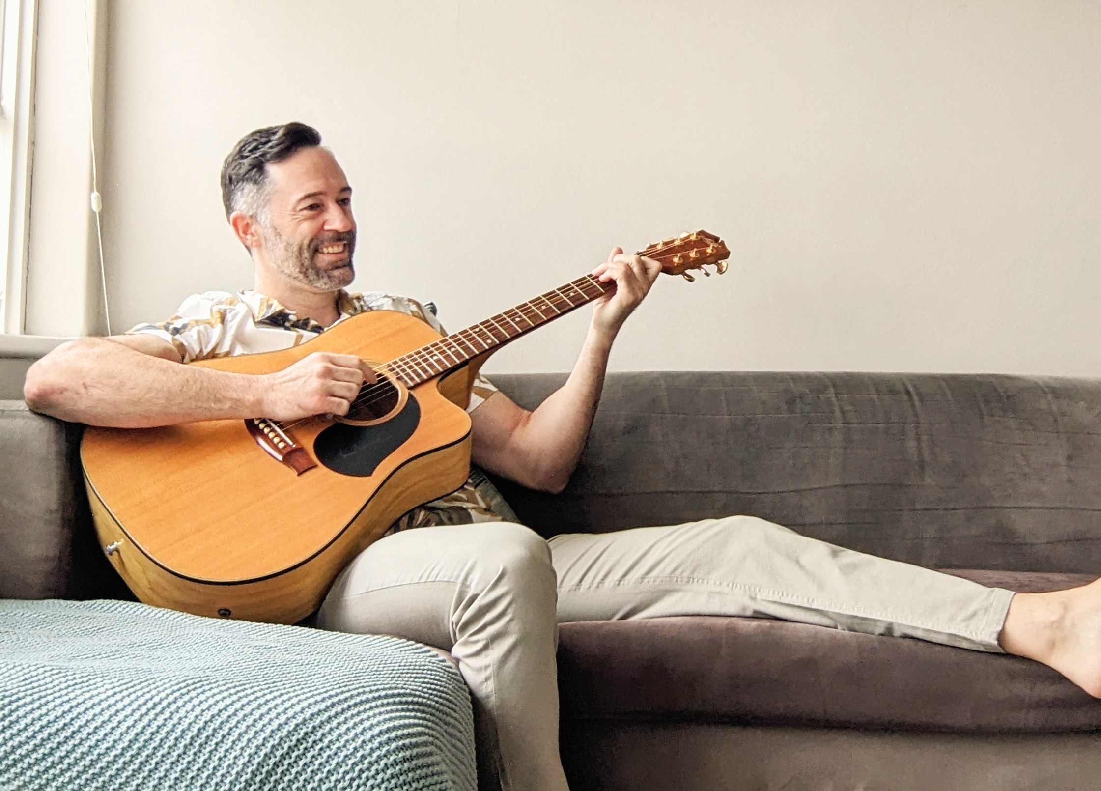 A man sitting on a couch playing a guitar